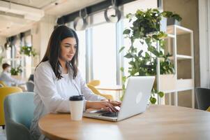 Smiling girl student study online with skype teacher, happy young woman learn language listen lecture watch webinar write notes look at laptop sit in cafe, distant education photo