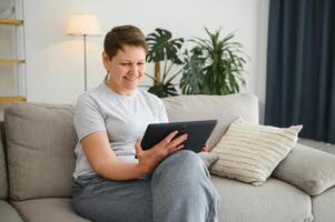 people, technology and internet concept - happy middle aged woman with tablet pc computer at home. photo