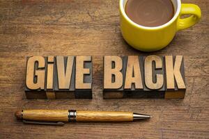 give back - words in vintage letterpress wood type against rustic wooden background with coffee, generosity and repay concept photo