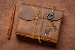 retro leather-bound journal with a decorative key and a luxurt pen on a handmade bark paper, journaling concept photo