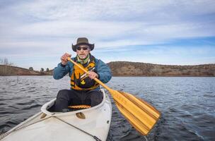 mayor masculino en vida chaqueta es remar expedición canoa, frío temporada paisaje en diente de caballo reservorio en del Norte Colorado, pov desde acción cámara foto