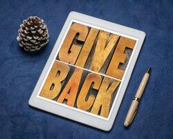 give back word abstract in vintage letterpress wood type on a digital tablet photo