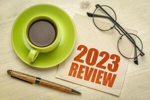 2023 year review text on a napkin with a cup of coffee, end of year business concept photo