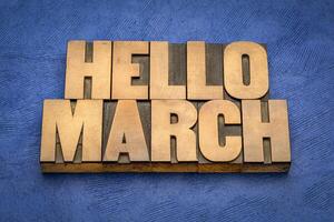 Hello March word abstract in vintage letterpress wood type against textured handmade paper, cheerful greetings photo