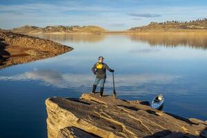 male canoe paddler with a paddle on  a rocky shore of a mountain lake - Horsetooth Reservoir in northern Colorado in fall or winter scenery photo