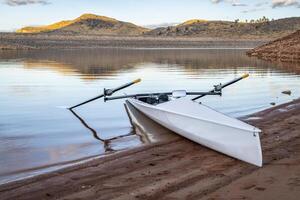 Coastal rowing shell on a shore of Horsetooth Reservoir in fall or winter scenery with a low water level. photo