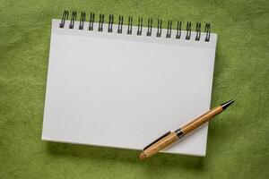 blanco espiral cuaderno con un lujo de madera bolígrafo en verde texturizado Arte papel foto