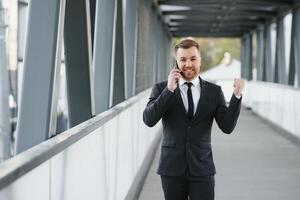 Businessman using smartphone in covered walkway. photo