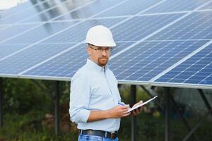 Solar energy. Young business man near the solar panels to power plants. photo