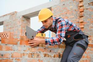 instalación de pared de ladrillo. trabajador de la construcción en uniforme y equipo de seguridad tiene trabajo en la construcción foto