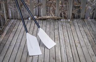 blades of hatchet sculling oars against grunge, rustic wooden deck photo