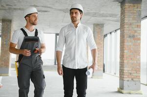 masculino arquitecto dando instrucciones a su capataz a construcción sitio. foto