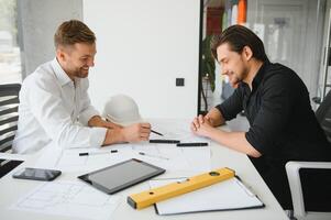 dos personas sentar en frente de construcción plan y hablar acerca de el arquitectura foto