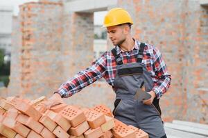 construction mason worker bricklayer installing red brick with trowel putty knife outdoors. photo