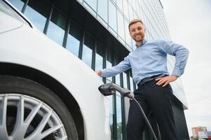 a businessman charges an electric car. photo