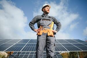 Male worker in uniform outdoors with solar batteries at sunny day. photo