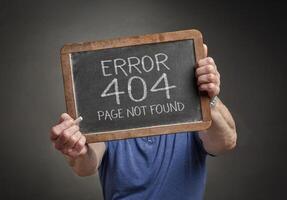 Page not found 404 error - white chalk text on a slate blackboard held by a person, HTTP status code photo