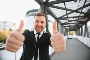 Successful businessman celebrating his victory with arms up on cityscape background. photo