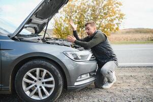 hombre comprobación su rompió abajo coche foto