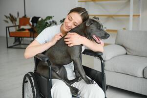 Young woman in wheelchair with service dog at home photo