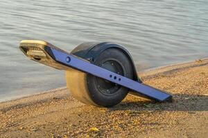 One-wheeled electric skateboard, personal transporter, on a lake shore in Colorado photo