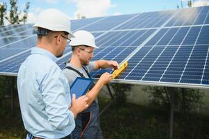 Male engineer in protective helmet installing solar photovoltaic panel system. Alternative energy ecological concept. photo