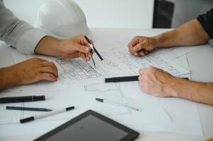 Two engineering working together and using digital tablet looking blueprint and analysis with architectural plan on desk photo