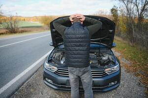 hombre con roto coche en el medio de el la carretera. foto