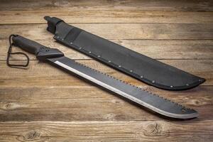 bush clearing machete with carbon steel blade and saw against rustic wooden deck photo