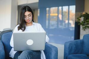 hermosa joven persona de libre dedicación mujer utilizando ordenador portátil computadora sentado a café mesa. contento sonriente niña trabajando en línea o estudiando y aprendizaje mientras utilizando cuaderno. Lanza libre trabajar, negocio personas concepto. foto