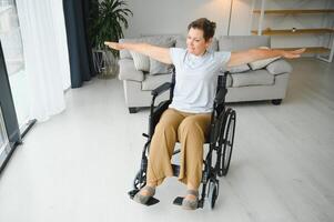 Woman in wheelchair working out in living room photo