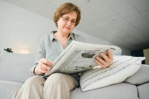 age and people concept - happy senior woman reading newspaper at home photo