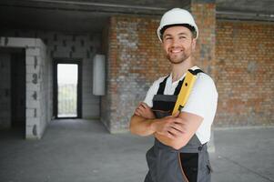 Man builder working in construction site. Male repairer in overall and helmet. photo