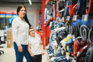 Mother and son shopping for electric vacuum cleaner, smiling photo