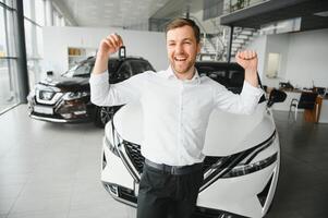 Yes, that's my new car. Customer in car dealership. Young man with keys in hand. photo