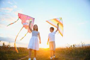 Happy children launch a kite in the field at sunset. Little boy and girl on summer vacation. photo