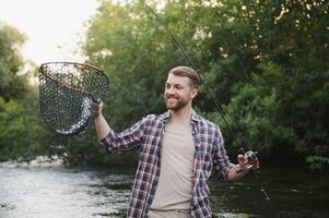 Fly-fisherman holding trout out of the water photo