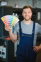 Man working in printing house with paper and paints photo