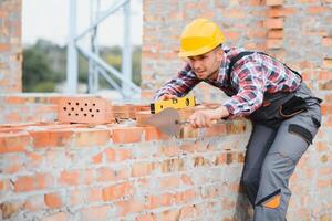 Yellow colored hard hat. Young man working in uniform at construction at daytime. photo