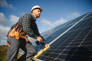 Professional worker installing solar panels on the metal construction, using different equipment, wearing helmet. Innovative solution for energy solving. Use renewable resources. Green energy. photo