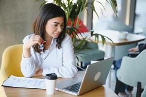 Smiling girl student study online with skype teacher, happy young woman learn language listen lecture watch webinar write notes look at laptop sit in cafe, distant education photo