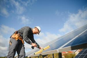 Professional worker installing solar panels on the metal construction, using different equipment, wearing helmet. Innovative solution for energy solving. Use renewable resources. Green energy. photo