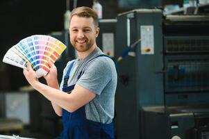 Man working in printing house with paper and paints photo