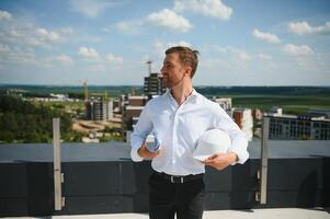 retrato de hombre arquitecto a edificio sitio. confidente construcción gerente vistiendo casco de seguridad. exitoso maduro civil ingeniero a construcción sitio con Copiar espacio. foto