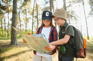 contento emocionado colegio niños con mochilas en casual ropa disfrutando caminar en bosque en soleado otoño día, dos activo niños chico y niña corriendo y jugando juntos durante cámping viaje en naturaleza. foto