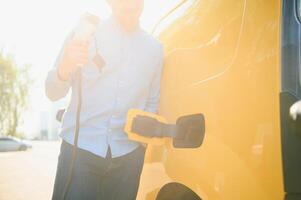 Man charging his electric car at charge station. photo