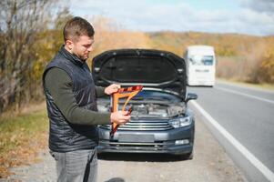 A young man with a black car that broke down on the road,copy space. photo