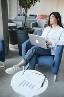 Beautiful Young Freelancer Woman Using Laptop Computer Sitting At Cafe Table. Happy Smiling Girl Working Online Or Studying And Learning While Using Notebook. Freelance Work, Business People Concept. photo