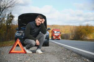 hombre con roto coche en el medio de el la carretera. foto