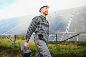 retrato de ingeniero en la seguridad casco y uniforme a solar poder estación instalando solar paneles verde energía. foto